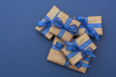 Noel ya da doğum günü hediyeleri. Mavi zemin üzerinde el işi kağıt paketlenmiş hediye kutuları, düz yatıyordu.
