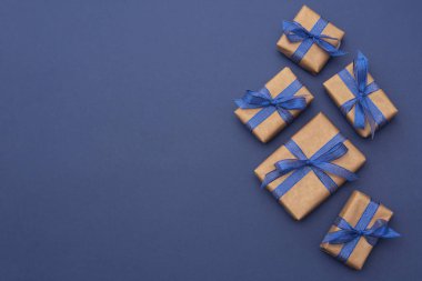 Noel ya da doğum günü hediyeleri. El işi kâğıdı, mavi arka planda paketlenmiş hediye kutuları, düz yatış. Boşluğu kopyala.