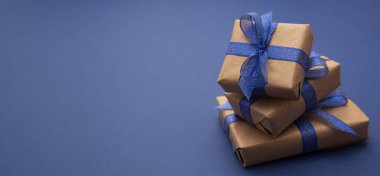 Hediyeli Noel afişi. El işi kâğıdı, mavi arka planda paketlenmiş hediye kutuları, düz yatış. Boşluğu kopyala.