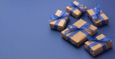 Noel afişi ya da doğum günü hediyeleri. El işi kâğıdı, mavi arka planda paketlenmiş hediye kutuları, düz yatış. Boşluğu kopyala.