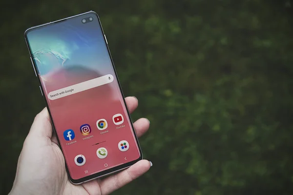 Corby, Birleşik Krallık. 25 Aralık 2019 Samsung Galaxy S10 cep telefonu, mavi arka planda beyaz S10 ile el ele tutuşuyor. İllüstrasyon Editörü