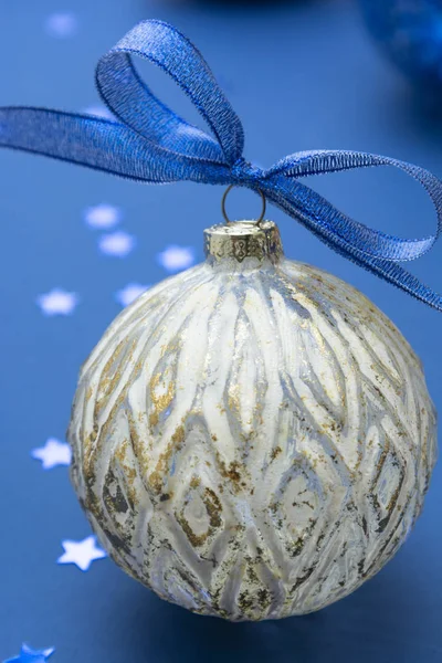 Рождественская безделушка с голубой лентой на синем фоне. Открытки на зимние праздники. Классический синий . — стоковое фото