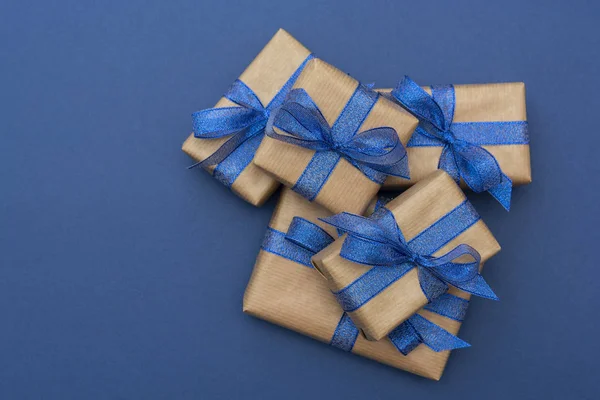 Noel ya da doğum günü hediyeleri. Mavi zemin üzerinde el işi kağıt paketlenmiş hediye kutuları, düz yatıyordu.