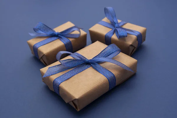 Close up gift boxes, presents. Craft paper wrapped gift boxes on blue background.
