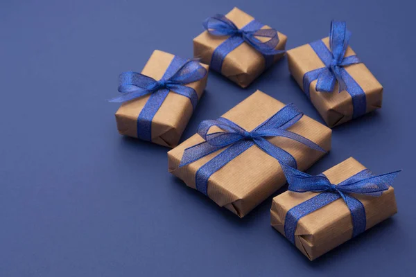 Cadeaux de Noël ou d'anniversaire. Craft papier enveloppé boîtes-cadeaux sur fond bleu, plat laïc . — Photo