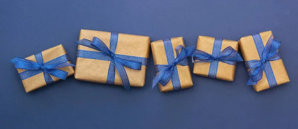 Papel artesanal envuelto cajas de regalo en una fila sobre fondo azul, plano con espacio de copia. Banner abstracto de Navidad . — Foto de Stock