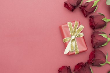 Sevgililer Günü, kırmızı güller ve kurdeleli hediye kutusu, kırmızı arka planda düz bir zemin, fotokopi alanı olan soyut doğum günü arkaplanı..