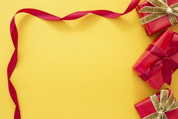 Ovanifrån av röda presentförpackningar med band över färgglada gul bakgrund. Alla hjärtans dag, jul eller födelsedag koncept. — Stockfoto