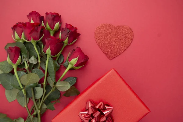 Rosas rojas y caja de regalo con cinta, sobre fondo rojo plano laico. Día de San Valentín, Fondo abstracto de cumpleaños con espacio para copiar . — Foto de Stock