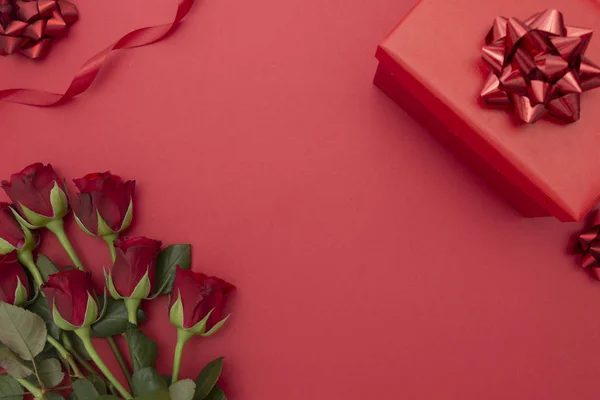 Красные розы и подарочная коробка с лентой, на красном фоне лежал плоский. День святого Валентина, день рождения абстрактный фон с копировальным пространством . — стоковое фото