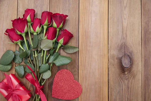Piros rózsák és ajándék doboz szalaggal, fából készült háttér lapos feküdt. Valentin nap, Születésnap elvont háttér másolási hely. — Stock Fotó