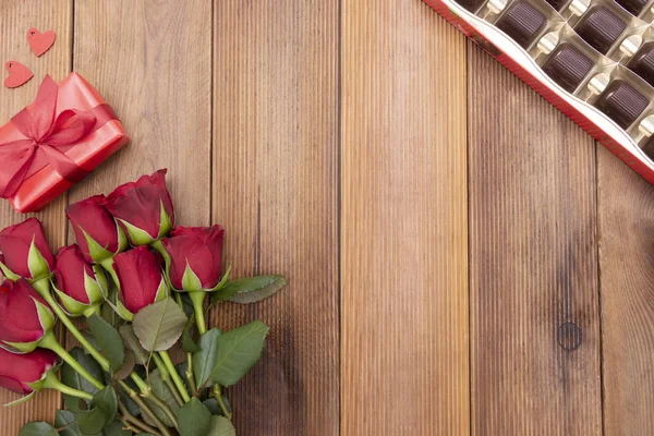 Día de San Valentín, rosas rojas, cajas de regalo y caja de chocolate con cinta, sobre fondo de madera plana, fondo abstracto de cumpleaños con espacio de copia . — Foto de Stock