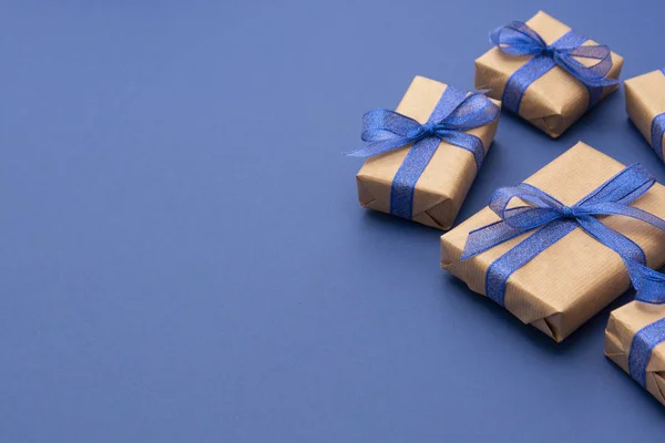 Vánoční nebo narozeninové dárky. Řemeslný papír zabalený v dárkových krabicích na modrém pozadí, plochý ležel. Kopírovat prostor. — Stock fotografie
