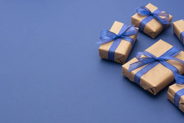 Noel ya da doğum günü hediyeleri. El işi kâğıdı, mavi arka planda paketlenmiş hediye kutuları, düz yatış. Boşluğu kopyala.