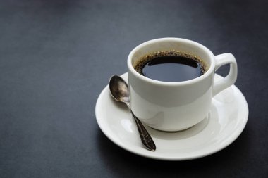 Kahve fincanı izole. Koyu arkaplanda beyaz kahve kaşığı ve tabak.