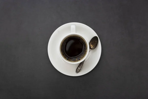 Coffee. White cup of coffee top view spoon and plate on dark background — Stock Photo, Image