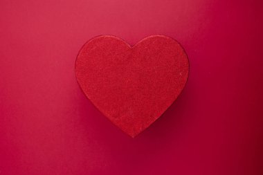 Kalp şeklinde parlak kırmızı kutu kırmızı arka planda izole edilmiş. Kopya alanı olan Sevgililer Günü hediyesi kutusu..