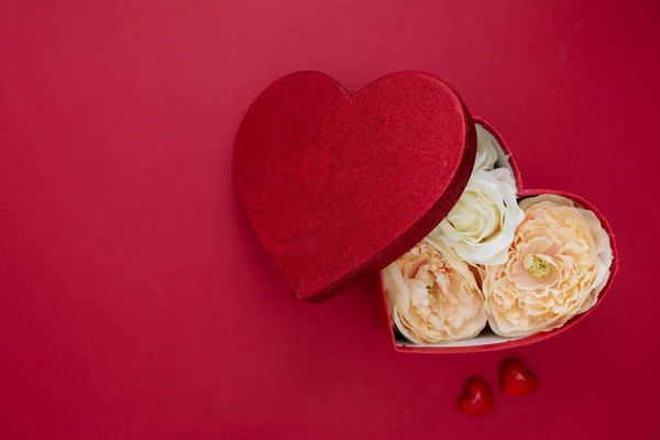 Caja de regalo en forma de corazón con flores sobre fondo rojo. Día de San Valentín burla con espacio para copias . — Foto de Stock