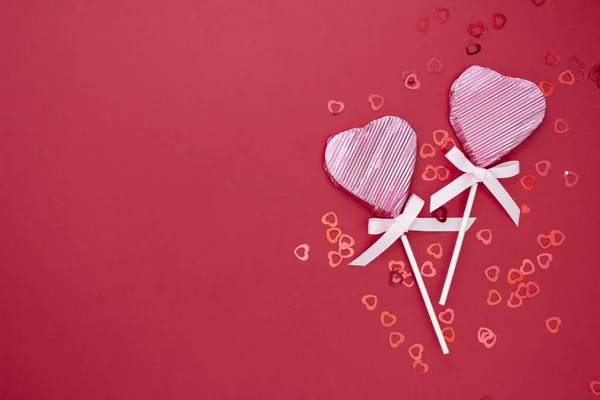 San Valentín maqueta, piruleta rosa en forma de corazón aislado sobre fondo rojo, con confeti, espacio de copia . — Foto de Stock