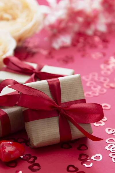 愛、バレンタインデーの背景。ギフトボックスは、クラフト紙と赤の背景に隔離された赤い弓で包まれて. — ストック写真