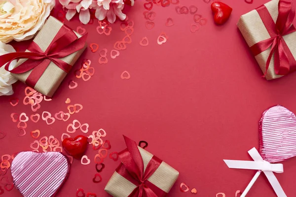 愛、バレンタインデーのフレームテンプレート。ギフトボックスは、クラフト紙と赤の背景に隔離された赤い弓で包まれて. — ストック写真