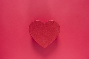 Kalp şeklinde parlak kırmızı kutu kırmızı arka planda izole edilmiş. Kopya alanı olan Sevgililer Günü hediyesi kutusu..