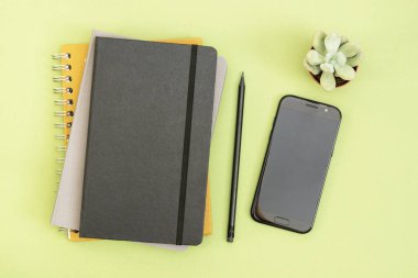 Çalışma masasının üst görüntüsü. Siyah kapalı defter, kahve fincanı ve akıllı telefon. Uzayı metin için kopyala. Tasarım modeli.