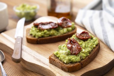Vejetaryen yemeği. Guakomole ile çavdar ekmeği, avokado makarna ve kurutulmuş domates, tahta kesme tahtasında. Avokado tostu.