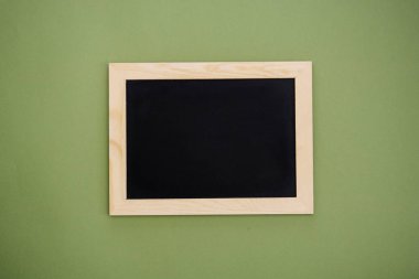 Ahşap çerçevedeki boş karatahta yeşil arka planda izole edilmiş. Tasarım için hazırlan.