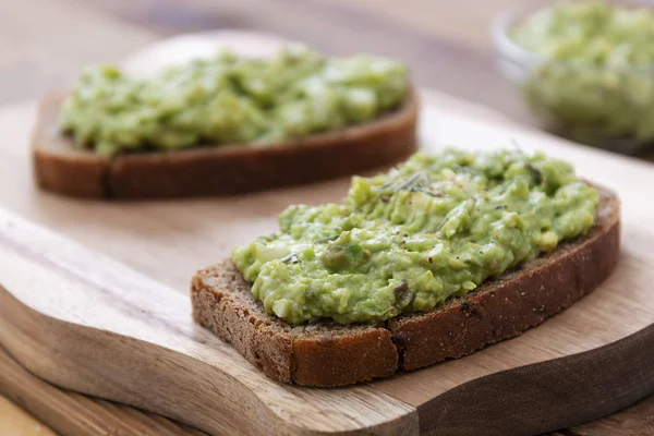 Sağlıklı yiyecekler. Guakomole ile çavdar ekmeği, ahşap kesim tahtasında avokado makarna. Kahvaltıda avokado tostu..