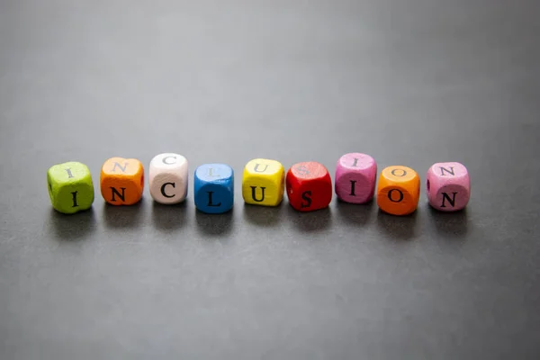 Inclusief tekst van multi gekleurde blokjes op donkere achtergrond. Inclusief sociaal concept. — Stockfoto