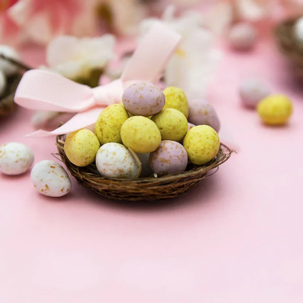 Velikonoční vajíčka v hnízdě na růžovém pozadí. Jarní přání s kopírovacím prostorem. — Stock fotografie