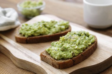 Sağlıklı yiyecekler. Guakomole ile çavdar ekmeği, ahşap kesim tahtasında avokado makarna. Kahvaltıda avokado tostu..