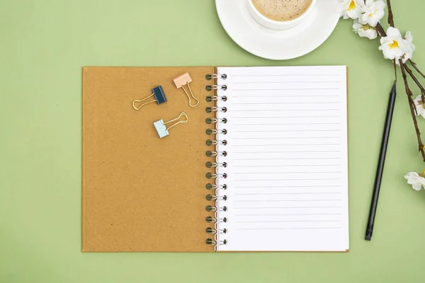 Abra o caderno com página vazia e xícara de café. Tampo da mesa, espaço de trabalho em fundo verde. Deitado plano criativo . — Fotografia de Stock