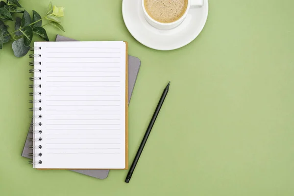 Ανοίξτε σημειωματάριο με άδεια σελίδα και φλιτζάνι καφέ. Επιφάνεια τραπεζιού, χώρος εργασίας σε πράσινο φόντο. Δημιουργική επίπεδη lay. — Φωτογραφία Αρχείου