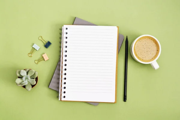 Abra o caderno com página vazia e xícara de café. Tampo da mesa, espaço de trabalho em fundo verde. Deitado plano criativo . — Fotografia de Stock