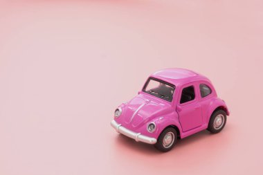 Pembe arka planda minyatür pembe oyuncak araba. Minimum konsept. Tebrik kartı maketi. Boşluğu kopyala.