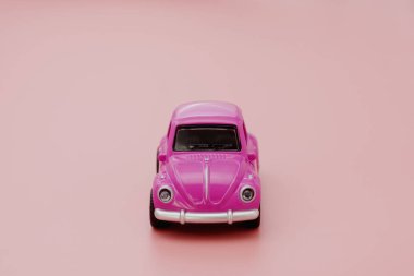 Pembe arka planda minyatür pembe oyuncak araba. Minimum konsept. Tebrik kartı maketi. Boşluğu kopyala.