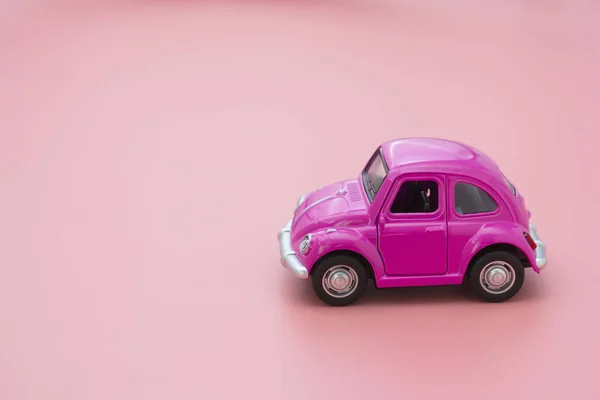 Miniature pink toy car on pink background. Minimal concept. Greeting card mock up. Copy space.
