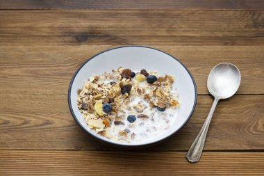 Yulaf ezmesi, tahıl gevreği, kurutulmuş meyve, yabanmersini, süt ve bal. Ahşap arka plan. Boşluğu kopyala.