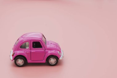 Corby, İngiltere 7 Şubat 2020. Pembe arka planda minyatür pembe oyuncak araba. Seyahat ulaşımı konsepti. Boşluğu kopyala.