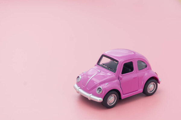 Corby, UK February 7, 2020. Миниатюрный розовый игрушечный автомобиль на розовом фоне. Минимальная концепция. Копирование пространства
.