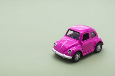 Corby, İngiltere 7 Şubat 2020. Yeşil arka planda minyatür pembe oyuncak araba. Araba sigortası konsepti. Boşluğu kopyala.