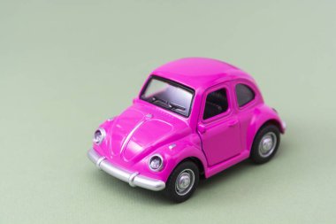 Corby, İngiltere 7 Şubat 2020. Yeşil arka planda minyatür pembe oyuncak araba. Minimum konsept. Boşluğu kopyala.