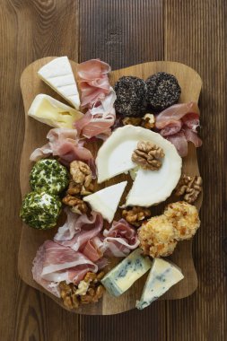 Peynir tabağı, çeşit çeşit peynir, üzüm, ceviz, bal ve prosciutto. Tahta kesme tahtası.
