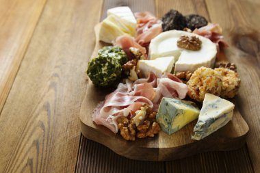 Peynir tabağı, çeşit çeşit peynir, üzüm, ceviz, bal ve prosciutto. Tahta kesme tahtası.