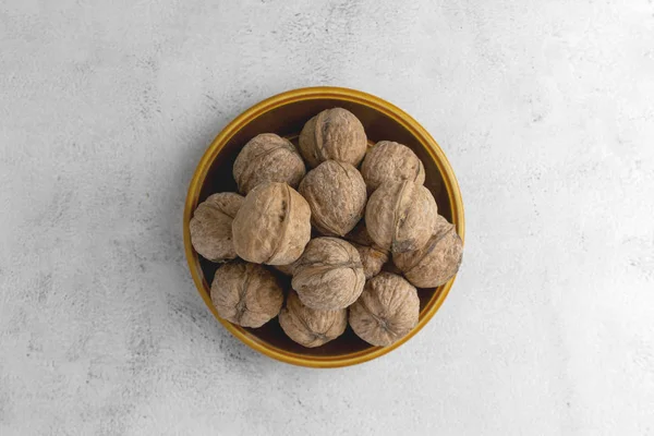 Walnuts in round plate on bright textured surface. Healthy nuts, healthy food. — Stock Photo, Image