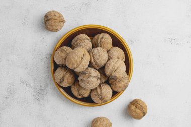 Parlak desenli yüzeyde yuvarlak tabakta cevizler. Sağlıklı fındık, sağlıklı yemek. Üst görünüm.