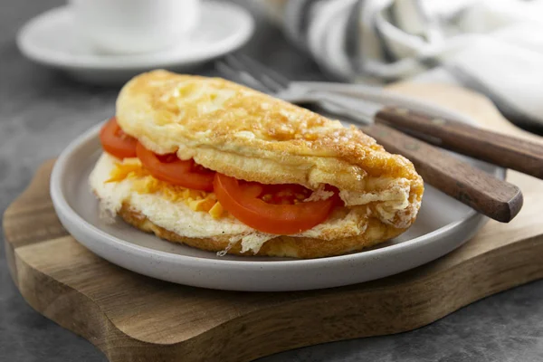 Peynirli omlet, domates ve bir fincan kahve. Kahvaltı için sağlıklı ev yapımı omlet. Koyu arkaplan.