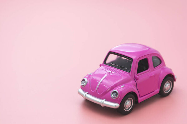 Corby, UK February 7, 2020. Миниатюрный розовый игрушечный автомобиль на розовом фоне. Минимальная концепция. Копирование текста
.